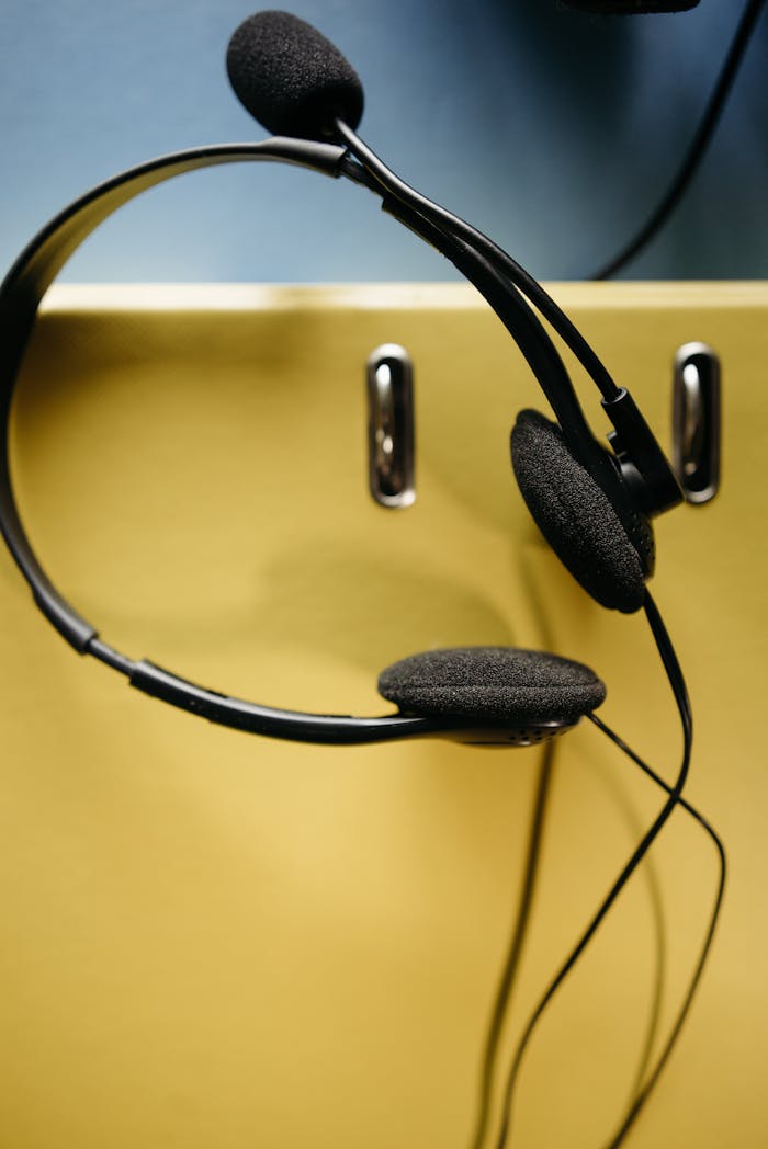 Close-up of a black headset hanging against a colorful yellow and blue background.